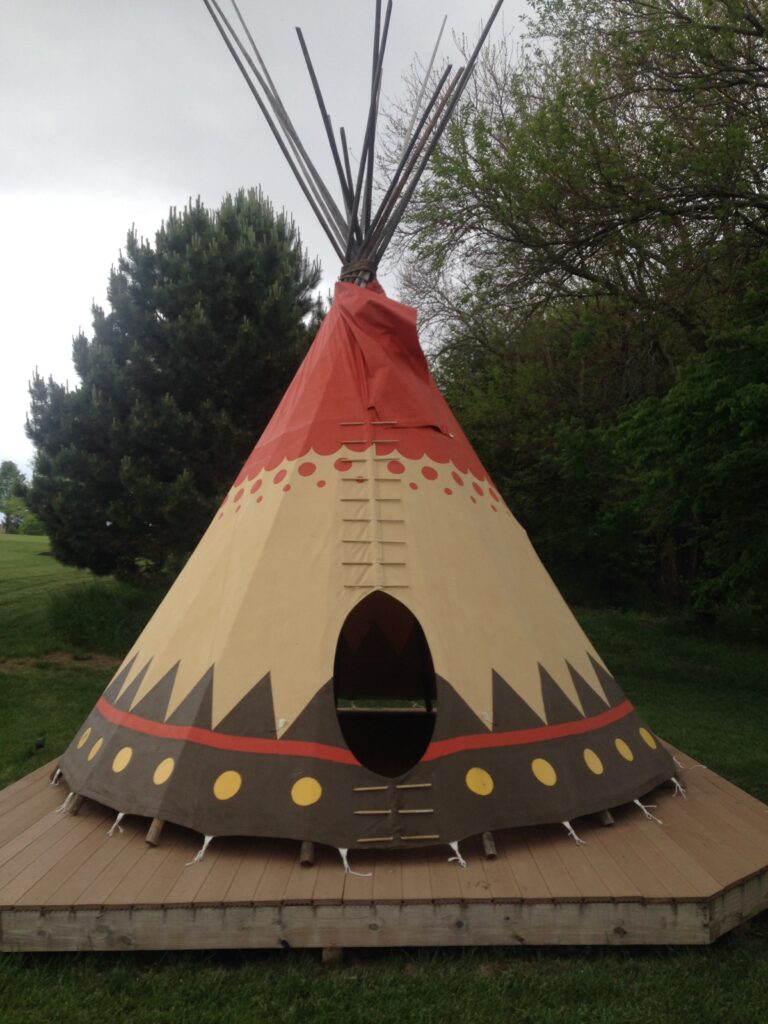 A teepee is painted red, yellow and black.