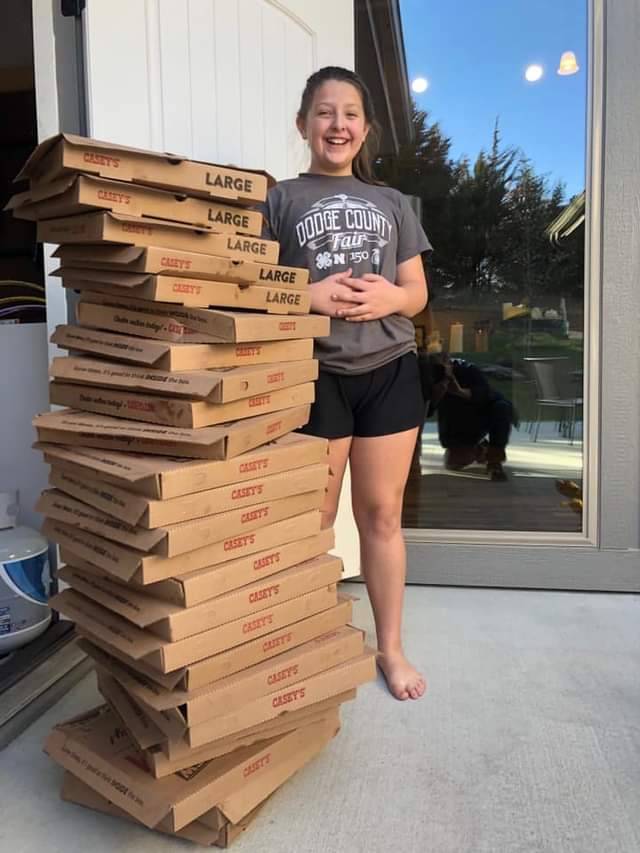 A woman standing next to a pile of pizza boxes.